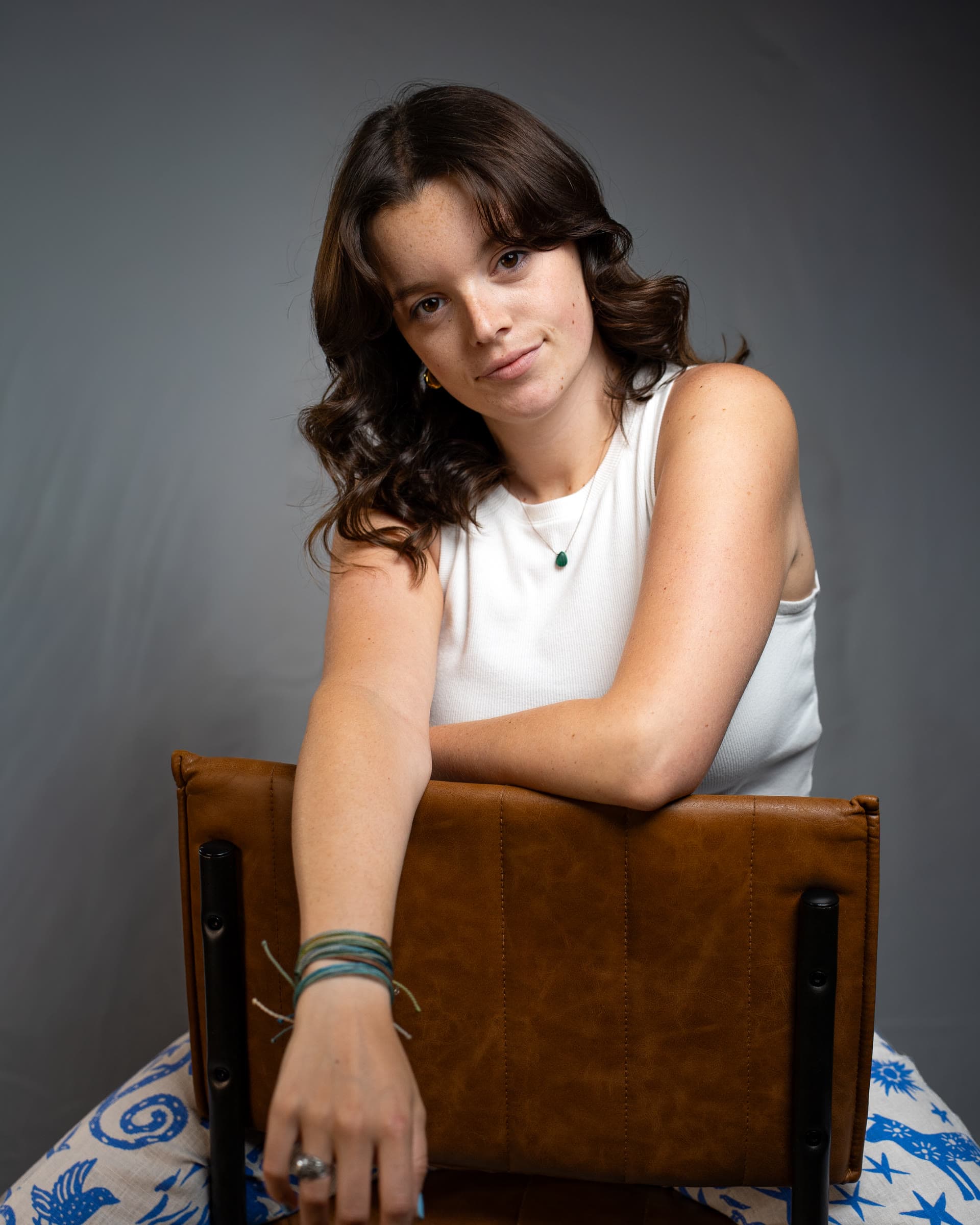 Editorial studio portrait, seated at a leather chair