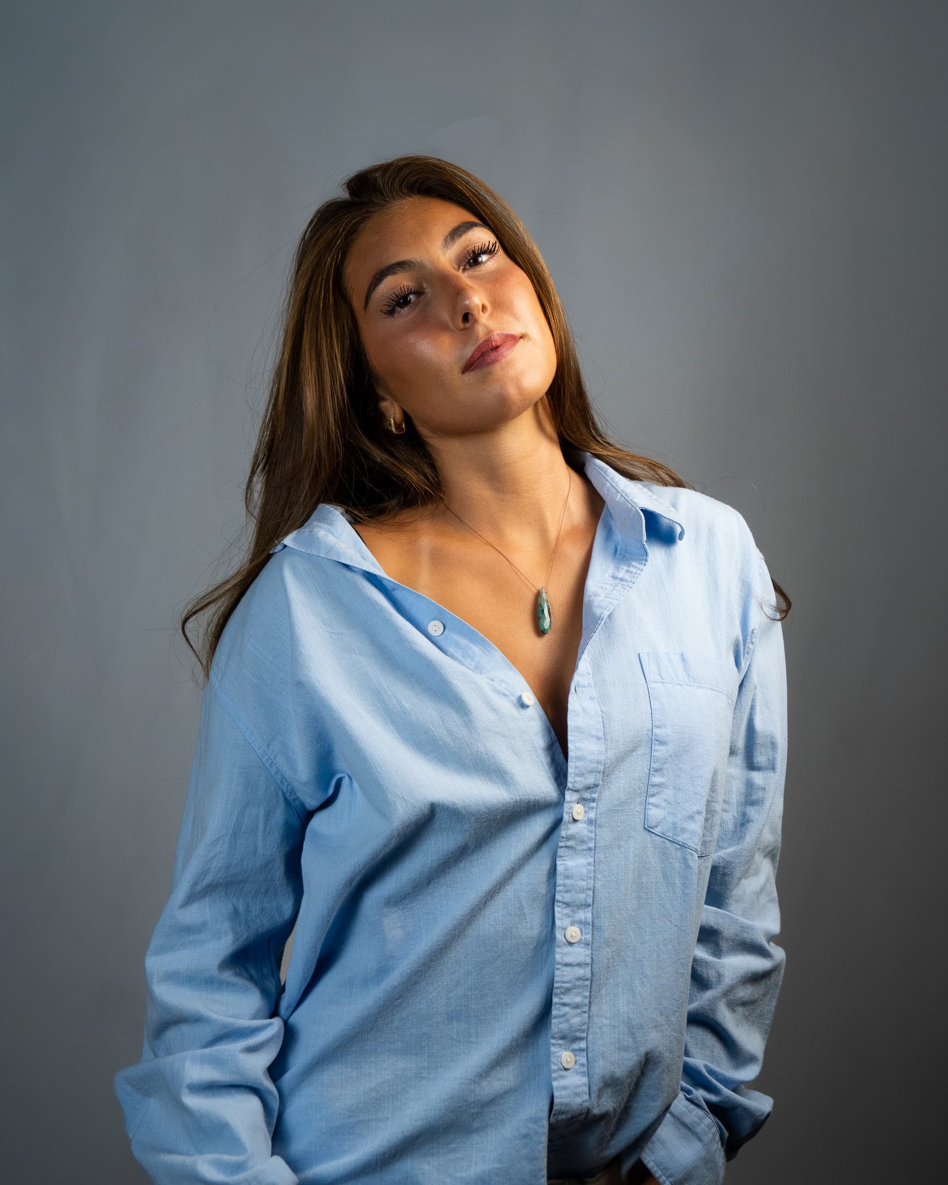 Studio headshot in a blue button-down against a grey seamless