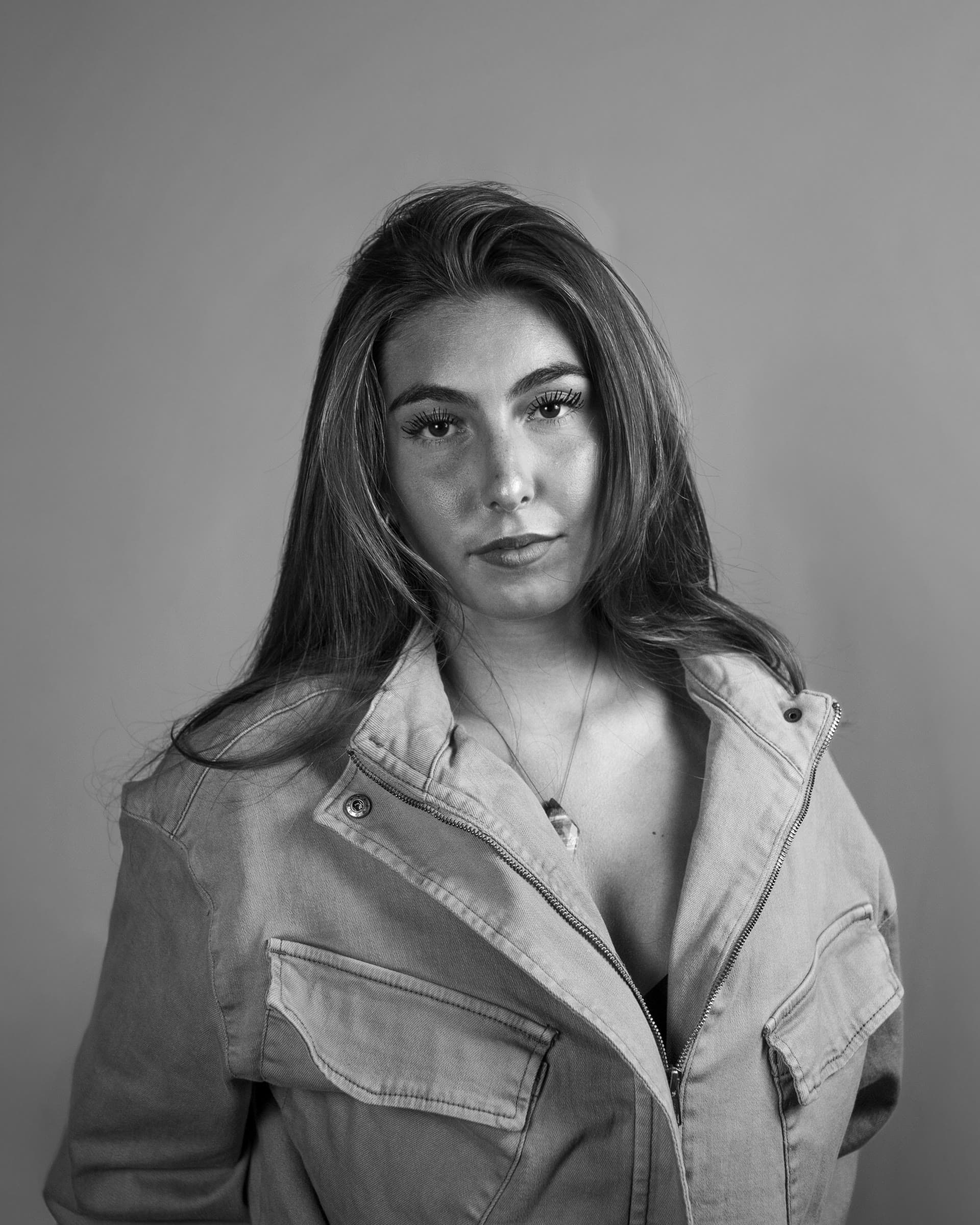 Black and white studio portrait of a woman in a denim jacket