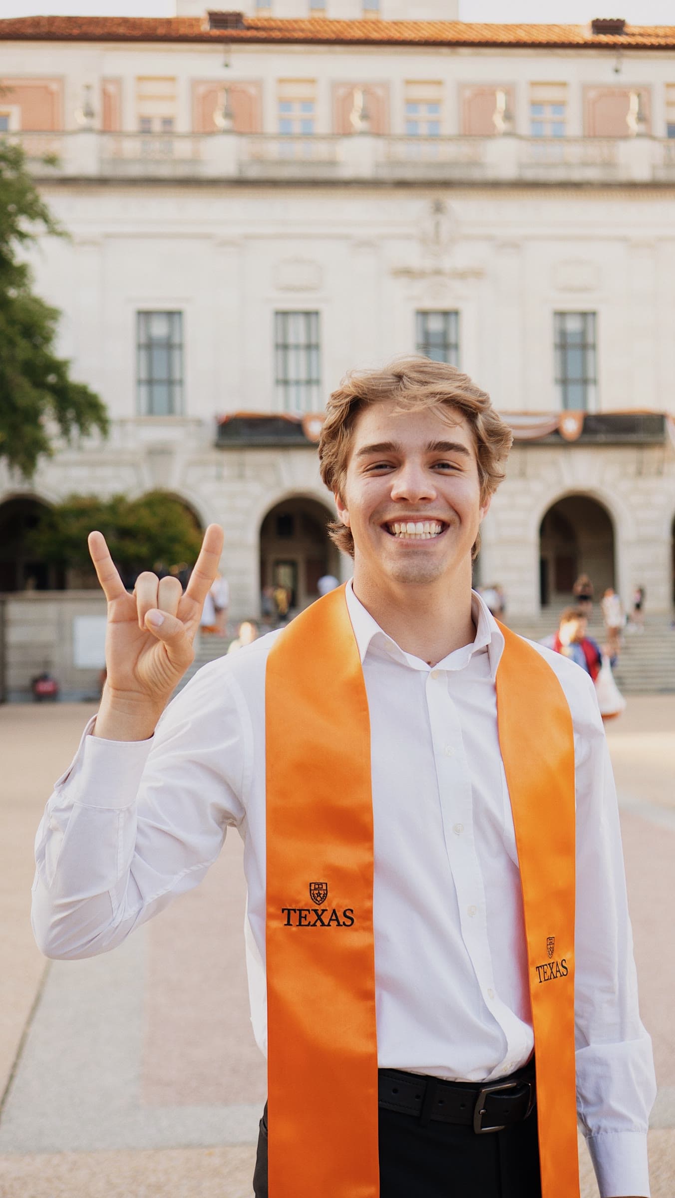 UT Austin graduate in an orange Texas stole on campus